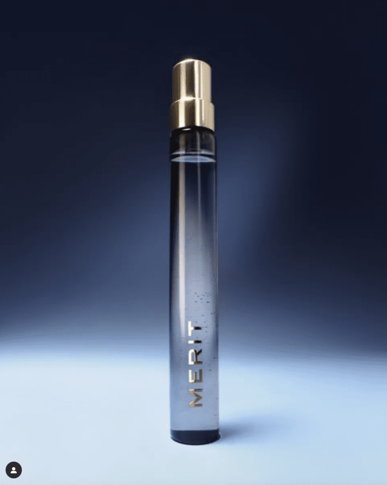 A tall clear cosmetic tube with a gold cap against a dark blue background.